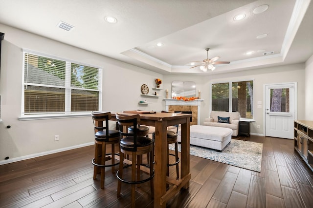 dining space featuring ceiling fan, a healthy amount of sunlight, dark hardwood / wood-style flooring, and a raised ceiling