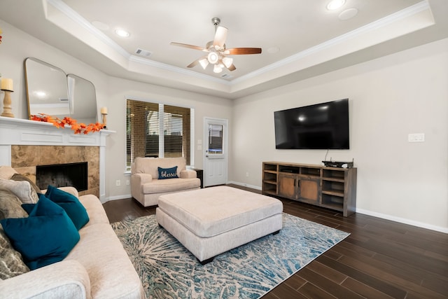 living room featuring ceiling fan, crown molding, a fireplace, and a tray ceiling