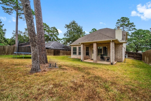 back of house with a lawn, a trampoline, and a patio area