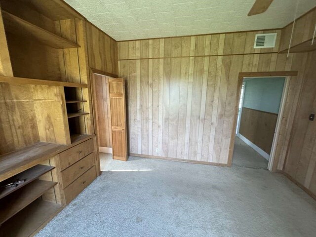 bedroom with wood walls and light colored carpet