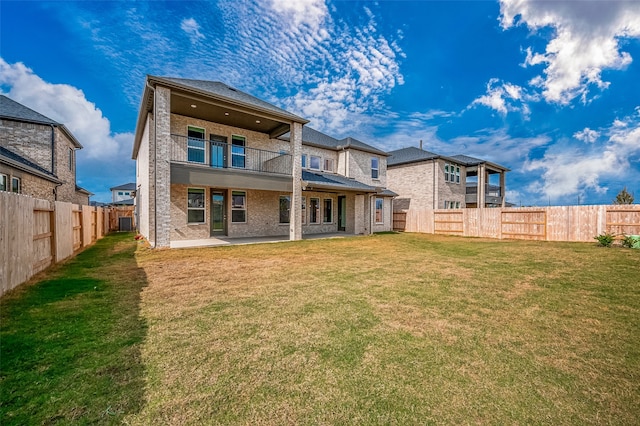 back of property with a yard and a balcony