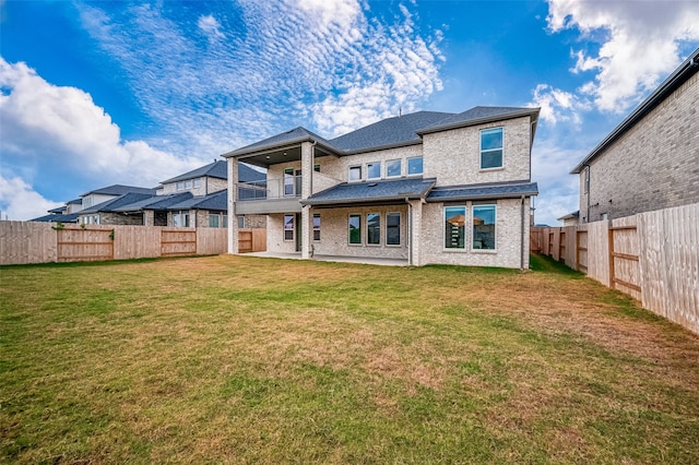 back of house with a balcony and a yard