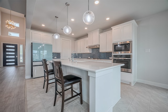 kitchen featuring white cabinets, stainless steel appliances, and hanging light fixtures