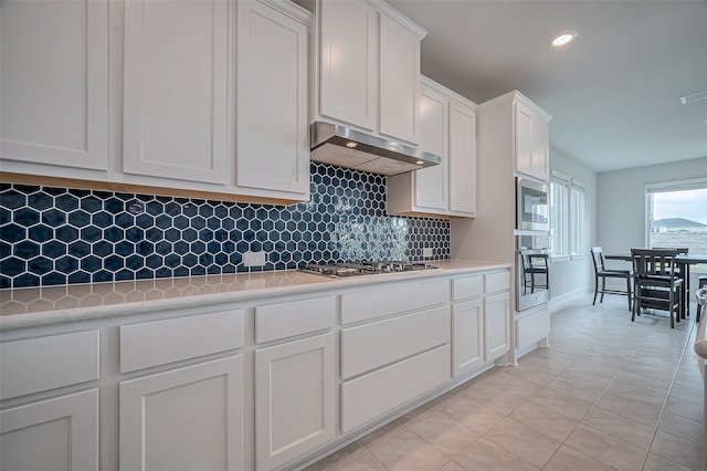 kitchen with white cabinets, light tile patterned floors, decorative backsplash, and appliances with stainless steel finishes