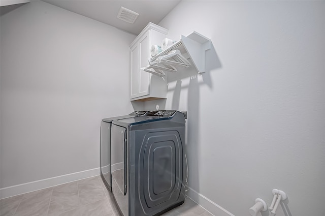 washroom with washing machine and dryer, cabinets, and light tile patterned floors