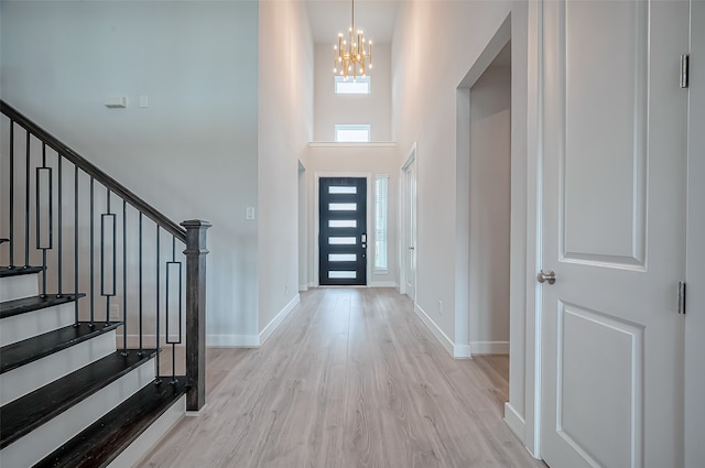 entrance foyer with a high ceiling, light wood-type flooring, and an inviting chandelier