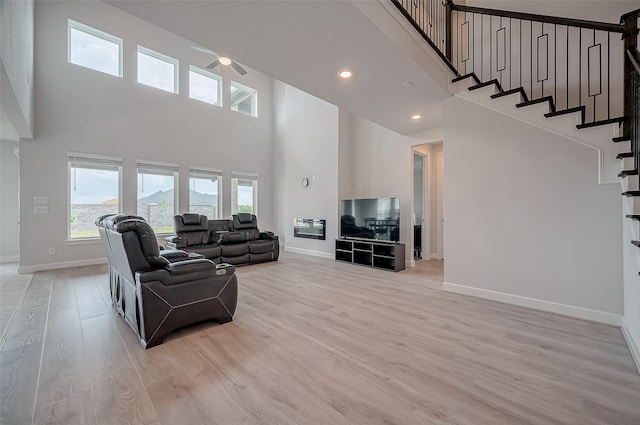 living room featuring a towering ceiling and light wood-type flooring