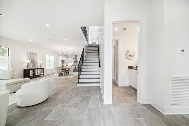 stairs featuring a healthy amount of sunlight, wood-type flooring, and a chandelier