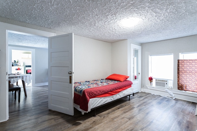 bedroom featuring a textured ceiling, cooling unit, and wood-type flooring