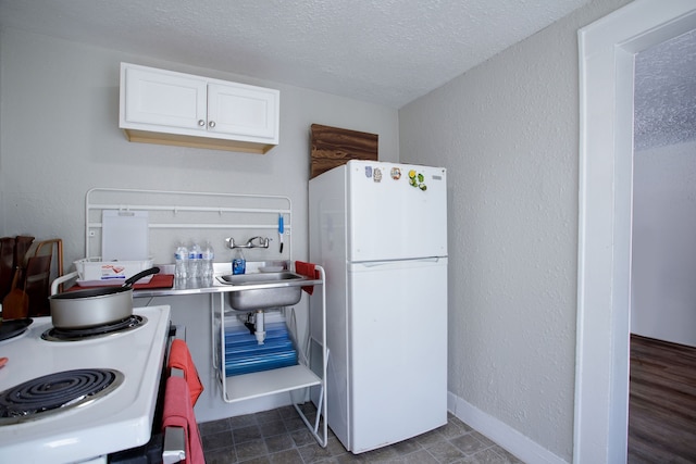 kitchen with dark hardwood / wood-style floors, sink, white cabinets, a textured ceiling, and white appliances