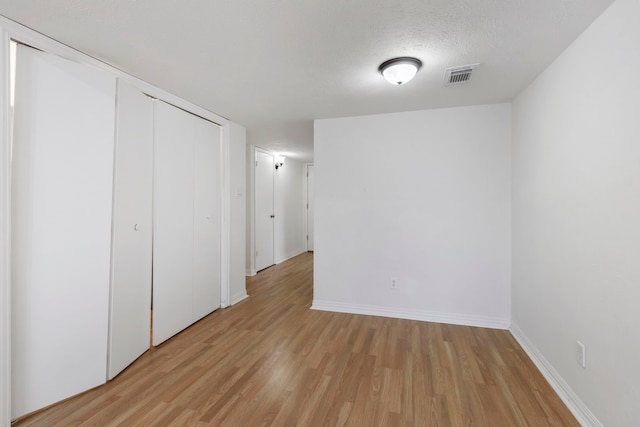 unfurnished bedroom featuring light hardwood / wood-style floors, a closet, and a textured ceiling