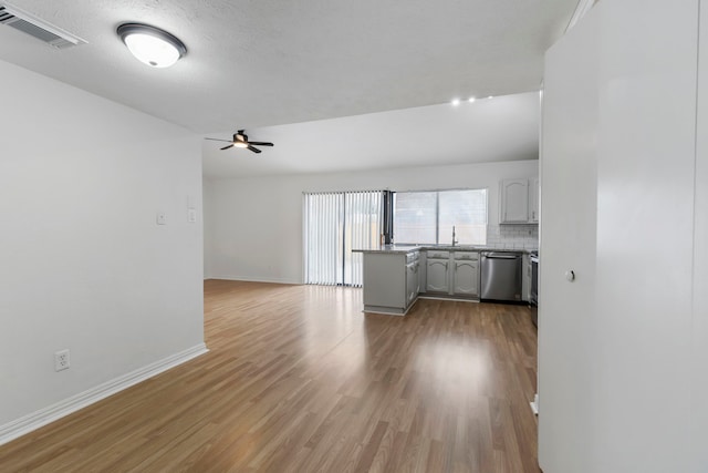 unfurnished living room featuring wood-type flooring, lofted ceiling, sink, ceiling fan, and a textured ceiling