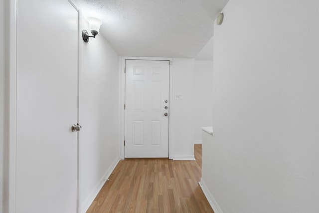 corridor with a textured ceiling and light wood-type flooring