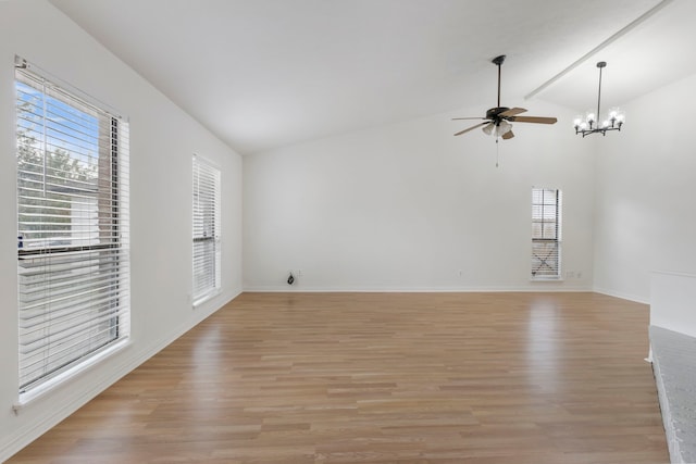 unfurnished living room featuring lofted ceiling, ceiling fan with notable chandelier, light hardwood / wood-style floors, and a healthy amount of sunlight