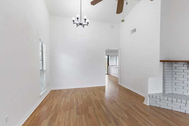 unfurnished living room featuring ceiling fan, a brick fireplace, high vaulted ceiling, and light hardwood / wood-style flooring