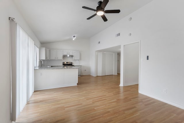 unfurnished living room featuring ceiling fan, high vaulted ceiling, sink, and light wood-type flooring