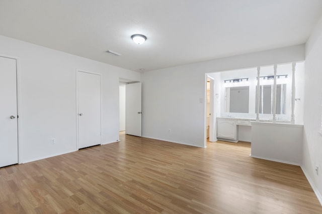 unfurnished bedroom featuring ensuite bath and light hardwood / wood-style flooring