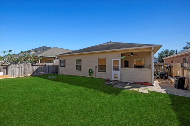 rear view of property featuring ceiling fan and a lawn