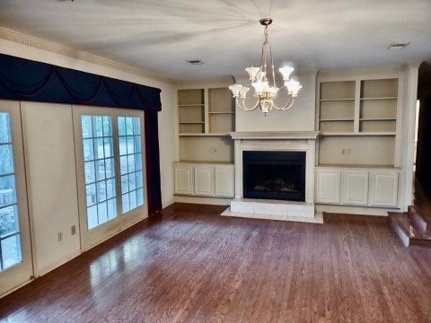 unfurnished living room featuring a notable chandelier, dark hardwood / wood-style floors, and built in features