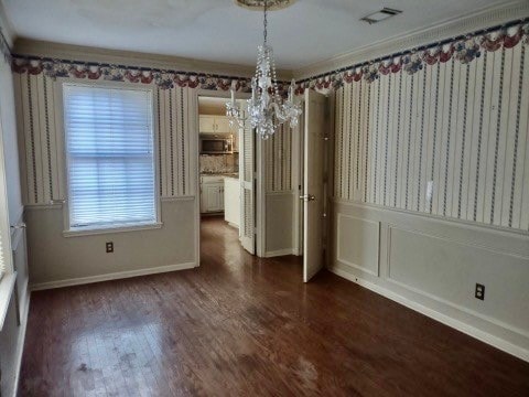 unfurnished dining area featuring an inviting chandelier and dark hardwood / wood-style floors