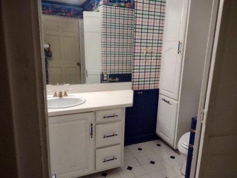 bathroom with toilet, vanity, and tile patterned flooring