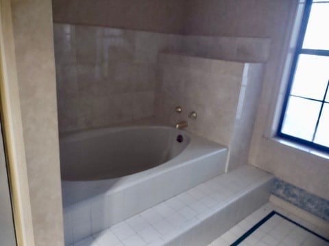 bathroom with tile patterned flooring and tiled tub