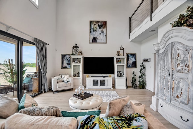 living room featuring a towering ceiling and light wood-type flooring