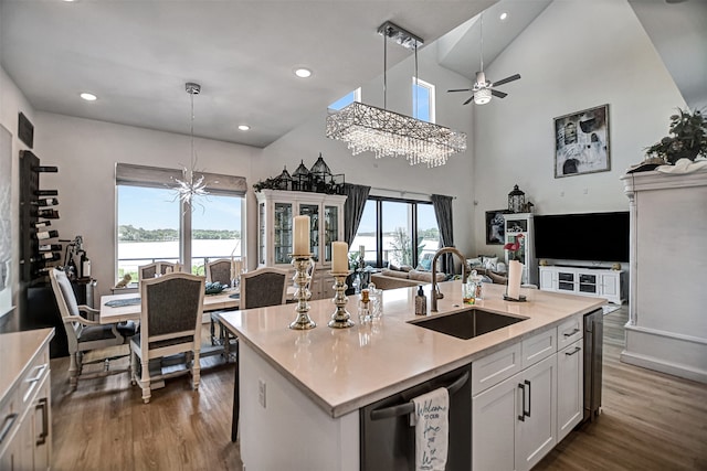 kitchen featuring white cabinets, an island with sink, dishwasher, pendant lighting, and sink