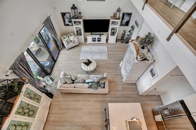 living room featuring light wood-type flooring and a towering ceiling