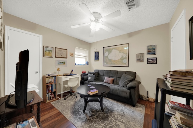 living room featuring a textured ceiling, dark hardwood / wood-style flooring, and ceiling fan