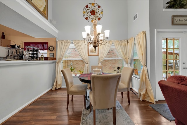 dining room featuring french doors, dark hardwood / wood-style flooring, a notable chandelier, and a high ceiling