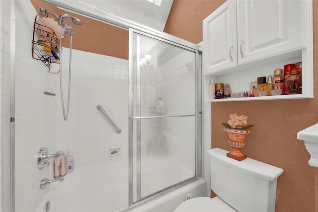 bathroom featuring toilet and combined bath / shower with glass door