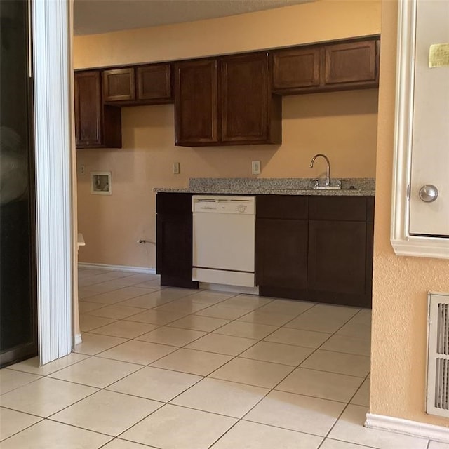 kitchen featuring white dishwasher, sink, dark brown cabinetry, light tile patterned floors, and light stone counters