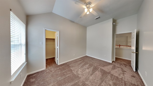 unfurnished bedroom with a spacious closet, ceiling fan, light carpet, and lofted ceiling