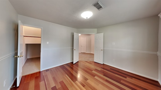 unfurnished bedroom featuring a closet, a walk in closet, and hardwood / wood-style floors