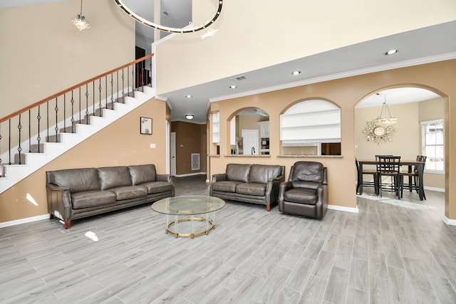 living room with crown molding, light hardwood / wood-style flooring, and a towering ceiling