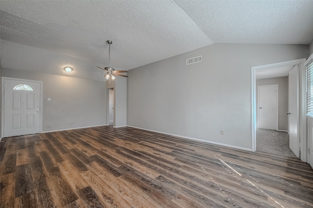 unfurnished living room with vaulted ceiling, dark hardwood / wood-style floors, and a textured ceiling