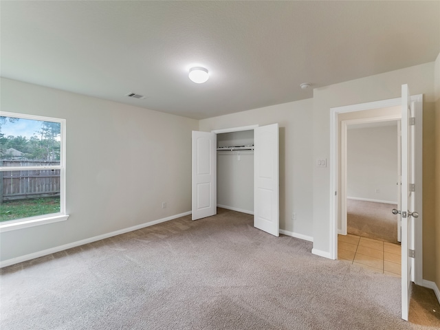 unfurnished bedroom with light carpet and a closet