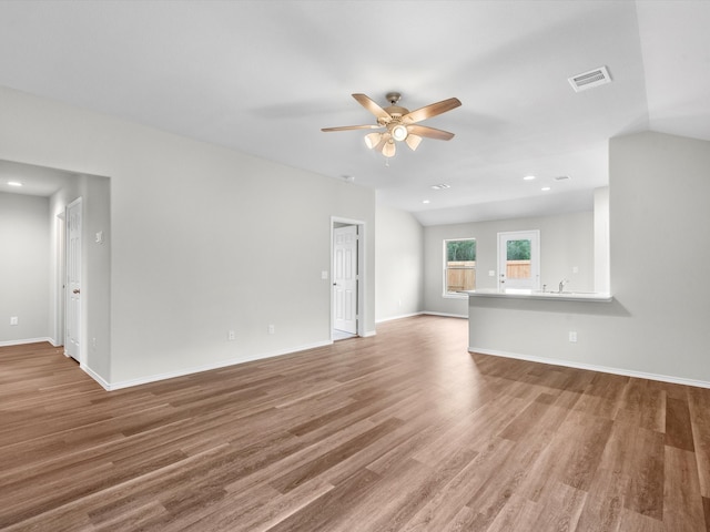 unfurnished living room featuring vaulted ceiling, wood-type flooring, and ceiling fan