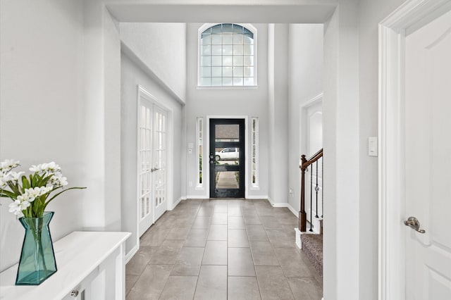 tiled entrance foyer with a high ceiling and french doors