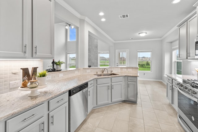 kitchen featuring sink, ornamental molding, stainless steel appliances, light stone counters, and decorative backsplash