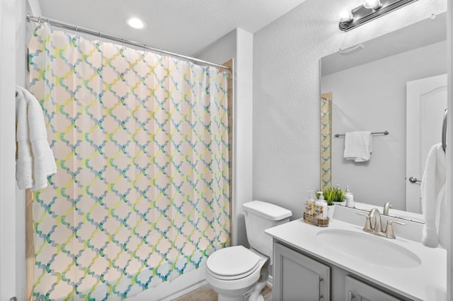 bathroom with vanity, a textured ceiling, toilet, and walk in shower