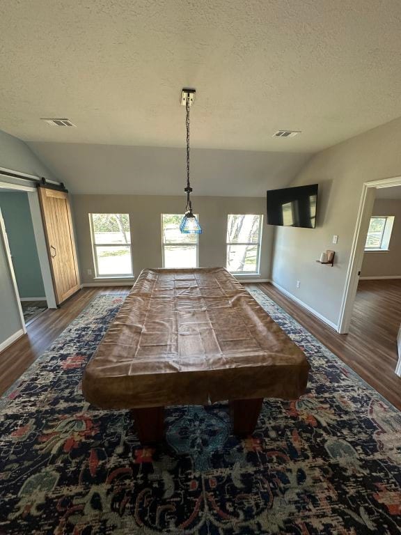 game room featuring hardwood / wood-style flooring, vaulted ceiling, plenty of natural light, and a barn door