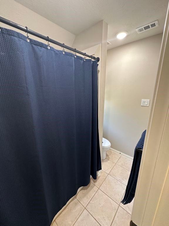 bathroom featuring tile patterned floors, toilet, and walk in shower