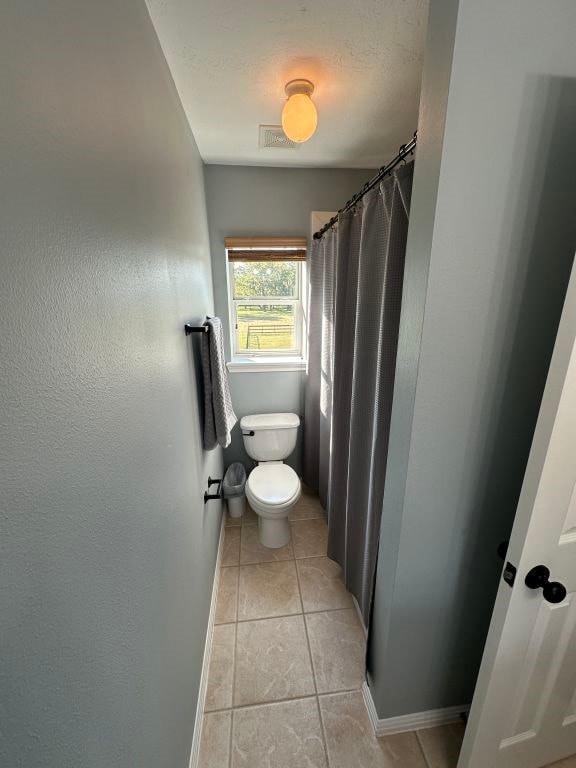 bathroom with tile patterned floors, toilet, and walk in shower