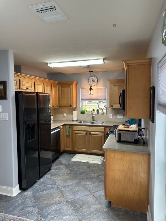 kitchen with sink, black appliances, hanging light fixtures, and tasteful backsplash