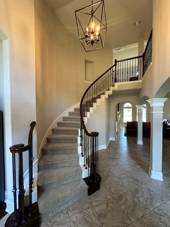 stairway with decorative columns and a towering ceiling