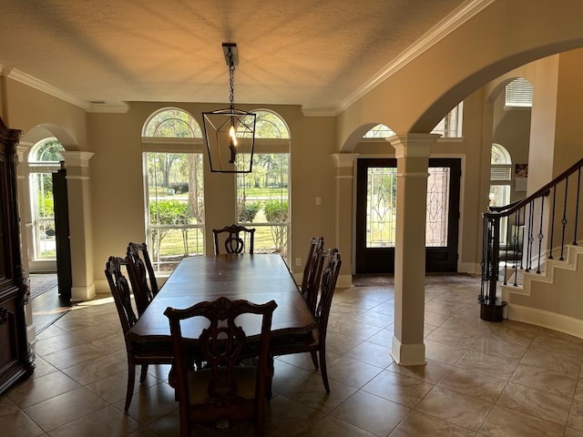 tiled dining area with ornamental molding, decorative columns, and a textured ceiling