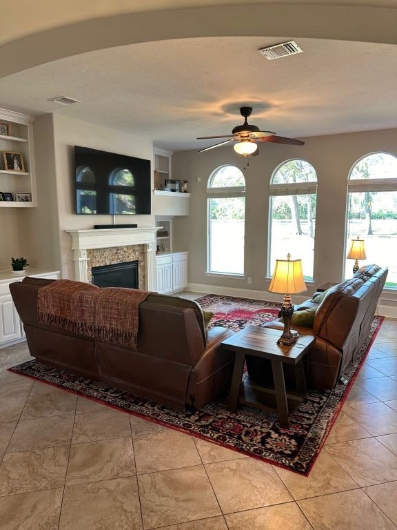 tiled living room featuring a healthy amount of sunlight, built in shelves, and ceiling fan