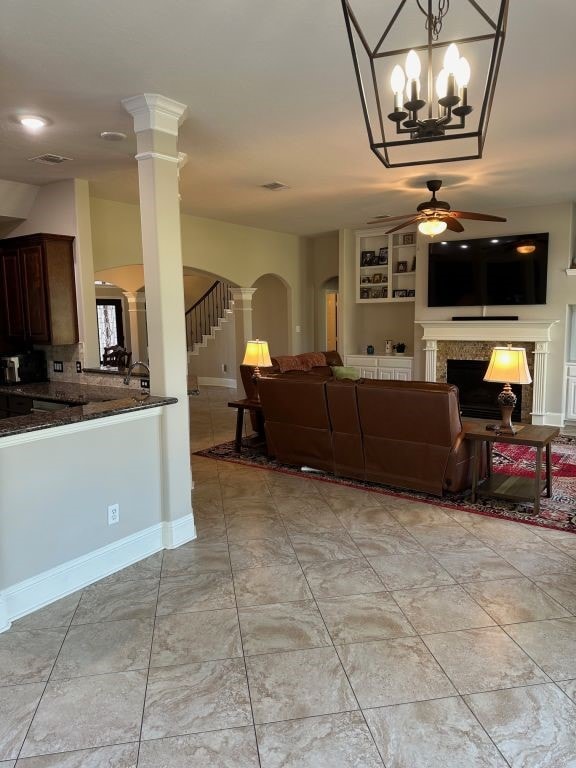 living room with ceiling fan with notable chandelier and decorative columns